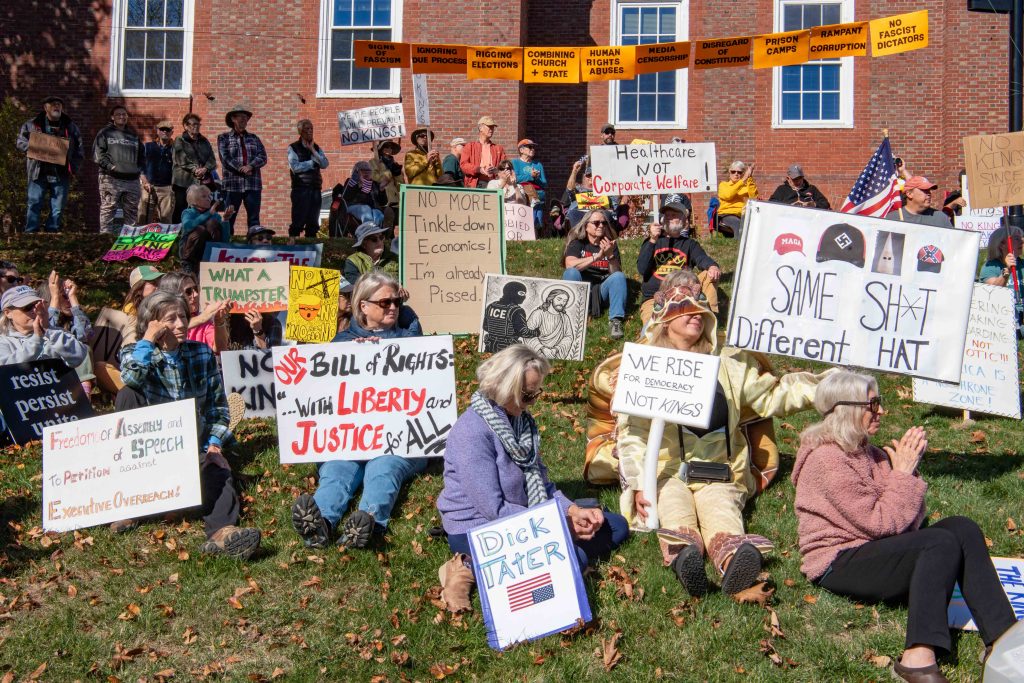 People sit on the hillside to protest and listen to speakers
