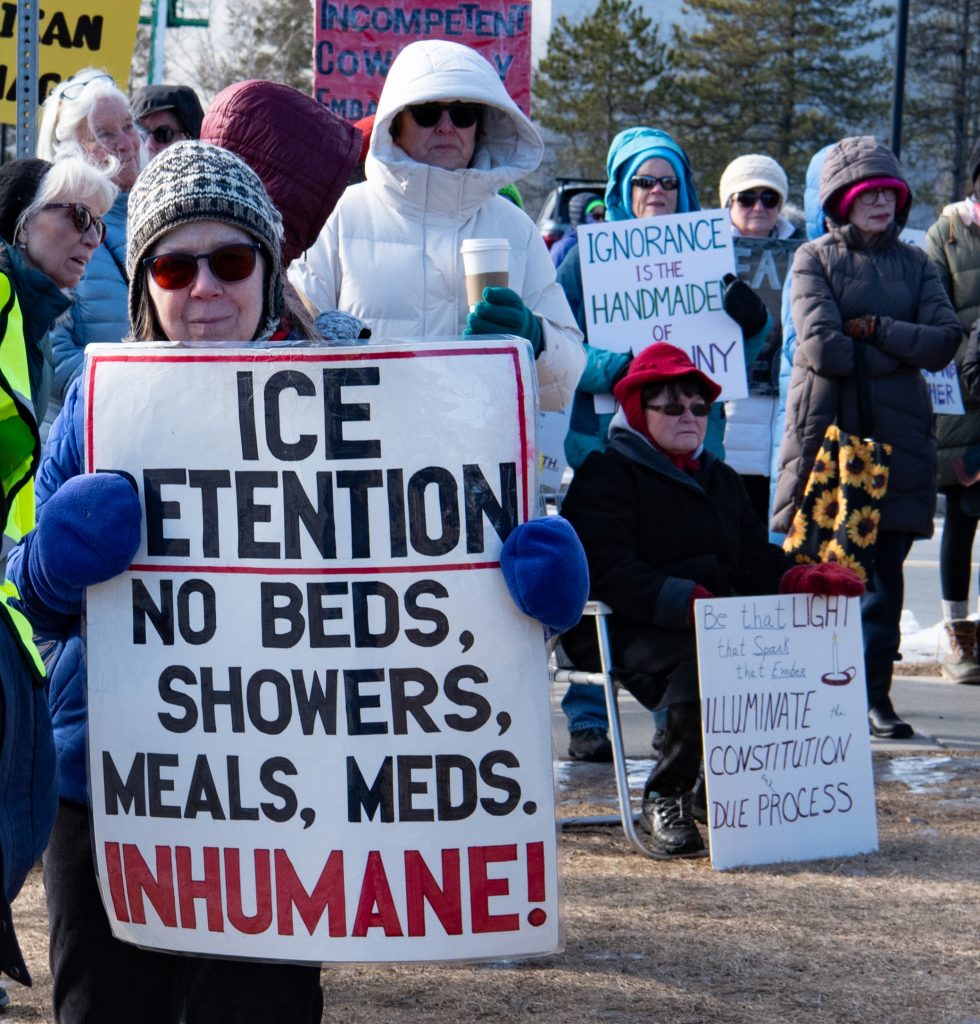 woman with sign: Ice Detention: No Beds, Showers, Meals, Meds.  Inhumane